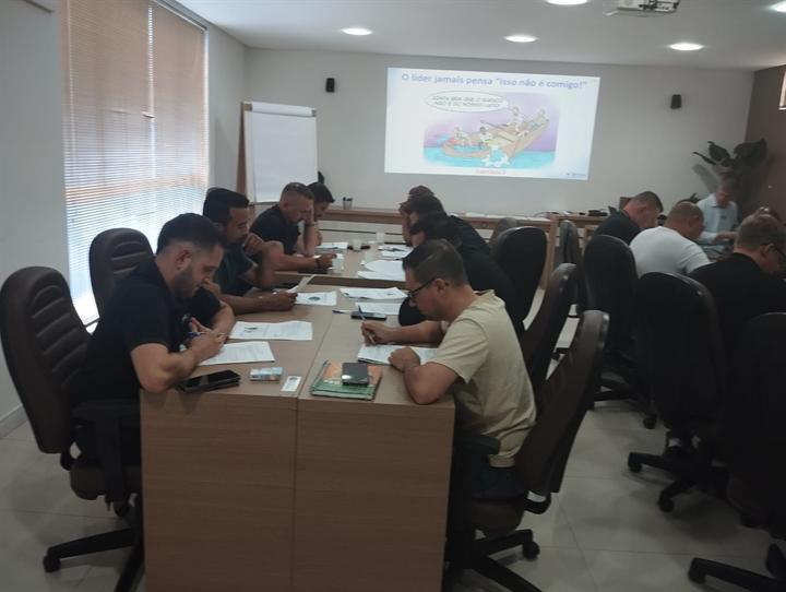 Participantes resolvendo exercício com slide sobre liderança ao fundo