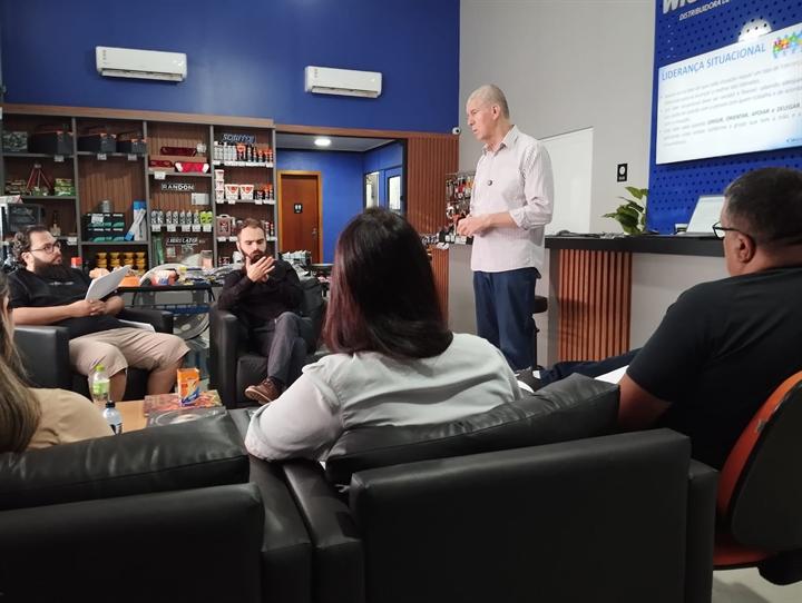 Instrutor conduzindo a aula para participantes sentados em sofás