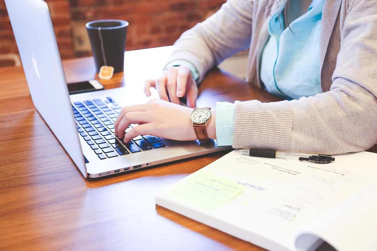 Pessoa trabalhando em um notebook com anotações ao lado